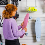 woman taking a penny board off flexipanel white slatwall